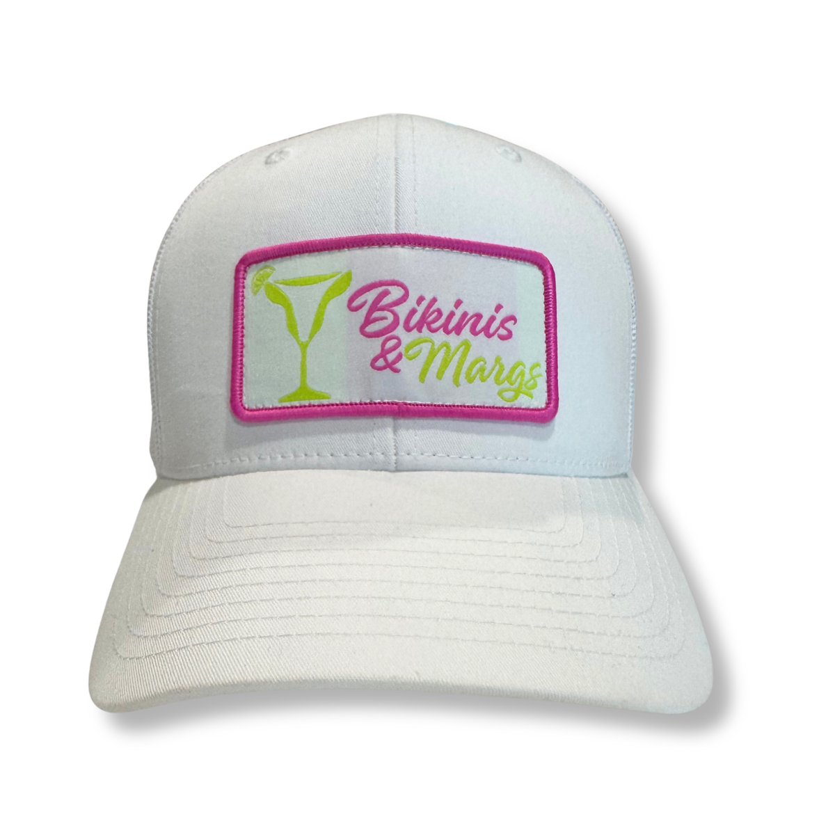 A white structured baseball cap featuring a rectangular embroidered patch on the front with a pink border, a green martini glass, and the text 'Bikinis & Margs' in pink and green script.