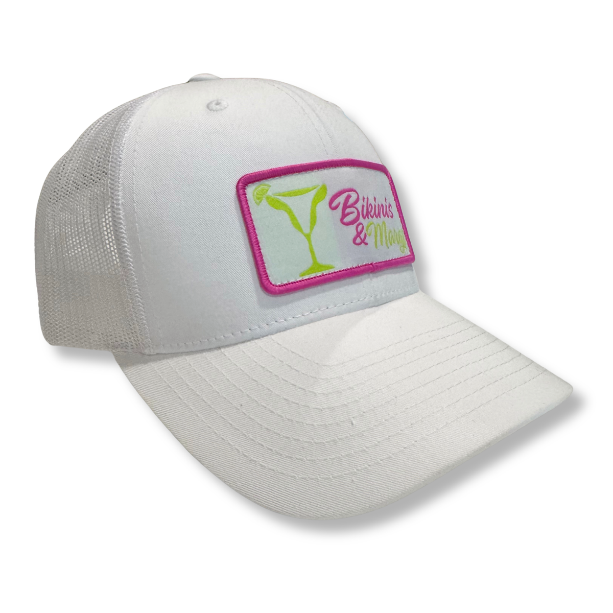 A white trucker-style baseball cap with a rectangular embroidered patch on the front. The patch features a pink border, a green martini glass graphic, and the text 'Bikinis & Margs' in pink and green.