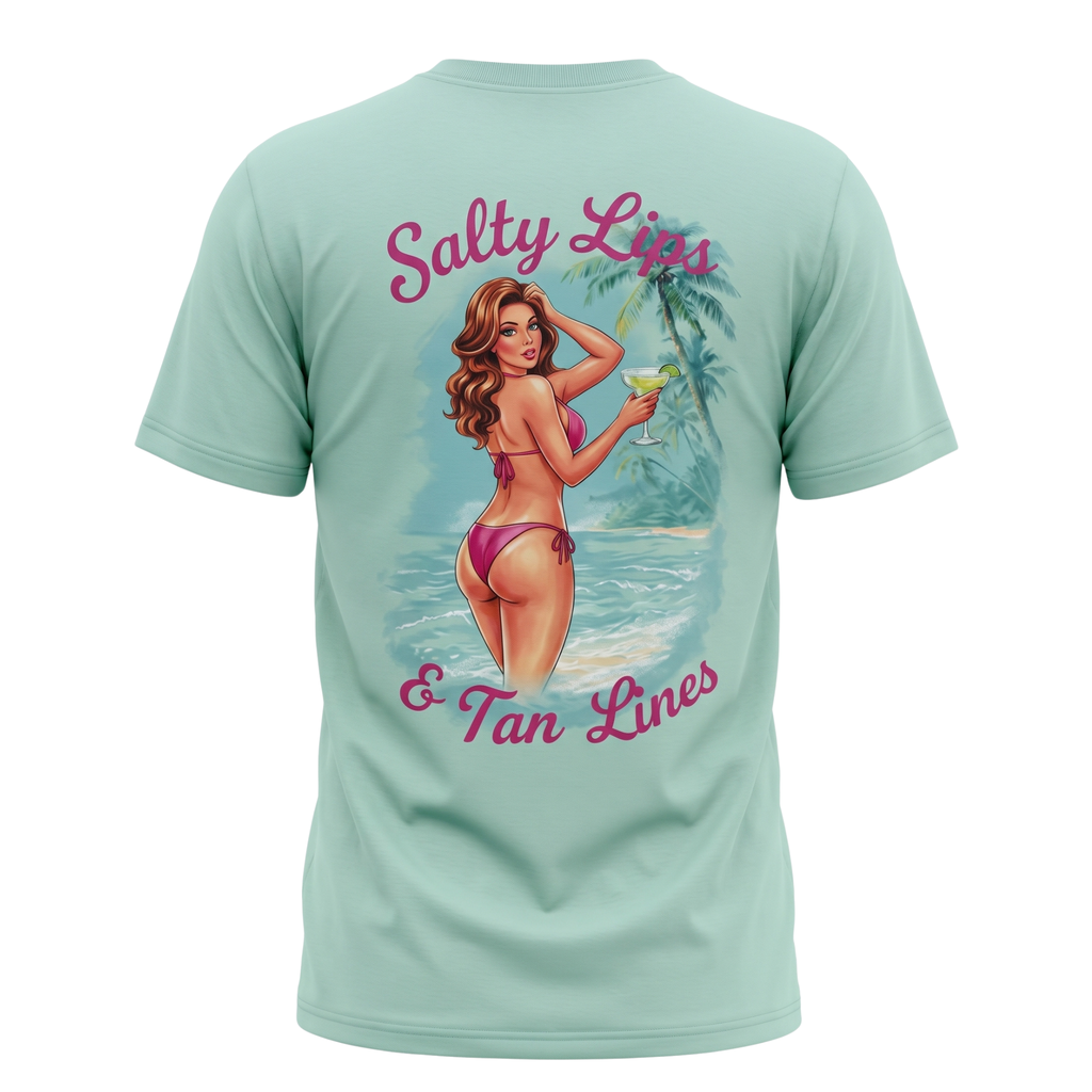 A mint green short-sleeve t-shirt shown from the back, featuring a large graphic print of a retro pin-up woman in a pink bikini on a tropical beach with the text 'Salty Lips & Tan Lines' in pink script.